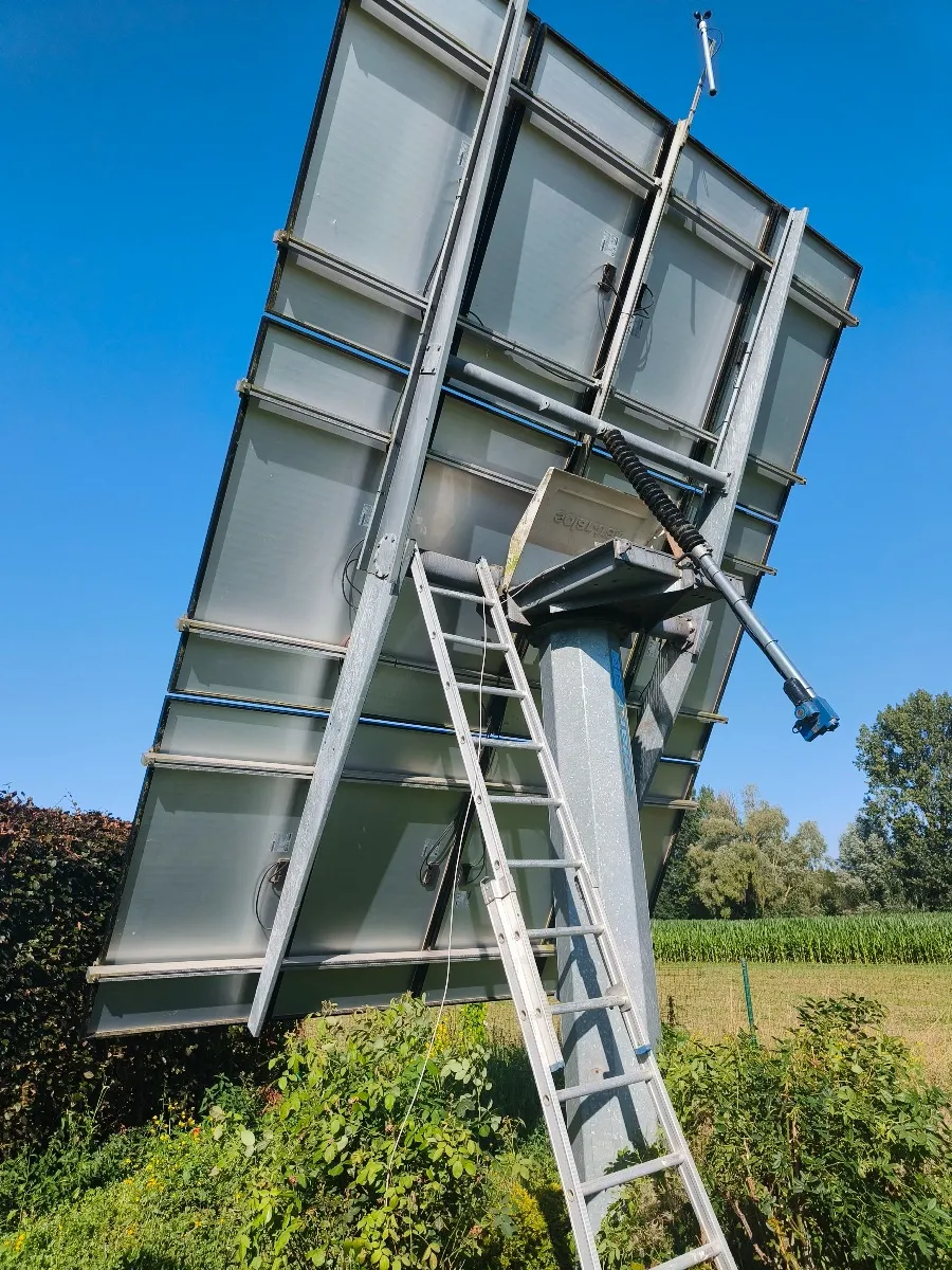 Technicien sur une échelle contre un tracker solaire